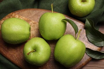Ripe green apples with leaves and water drops on wooden table, flat lay