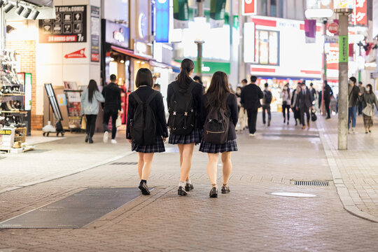 夜の渋谷センター街を歩く制服の女子高生の後ろ姿