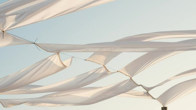 Waving white fabric on sunrise at the ocean beach on sunrise