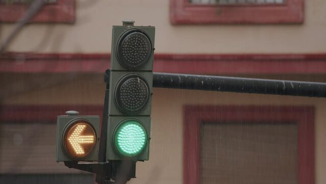 A traffic light hangs over the road on a city street during the rain