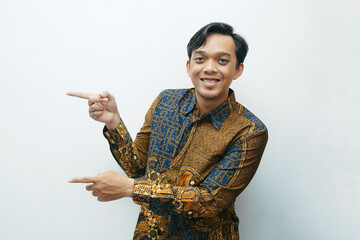 Portrait of Asian Indonesian man in Batik traditional shirt pointing using finger