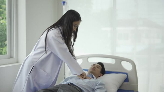 Asian female doctor gives first aid to a cardiac arrest patient by performing CPR on a hospital bed. The doctor uses a hand pump on his chest to provide first aid. CPR medical concept