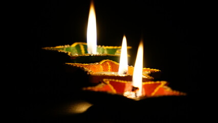 Happy Diwali, Lit Diya lamp on a black background.