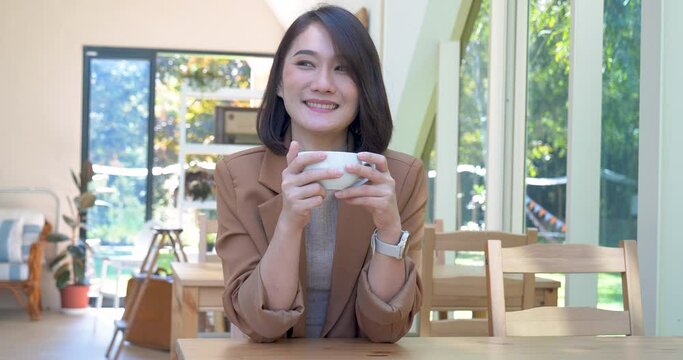 Asian Woman drink black coffee hand holding cup at green garden cafe. Young woman smile face love drink coffee. Beauty woman drinking black tea in coffee shop holding freshness cup. Women lifestyle