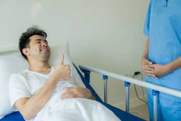 Asian male patient lies in bed while doctor examines and inquires about illness, female nurse...