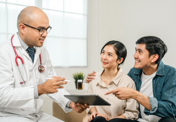 Asian family discussing fertility with a pediatrician. Young couple patients in fertility clinic consulting about IVF or IUI with doctor. Couple relationship therapy with a counselor