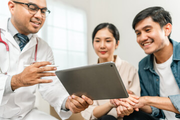 Asian family discussing fertility with a pediatrician. Young couple patients in fertility clinic consulting about IVF or IUI with doctor. Couple relationship therapy with a counselor