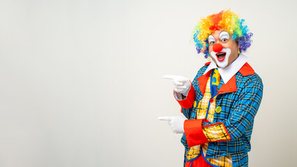 Mr Clown. Portrait of Funny comedian face Clown man in colorful uniform pointing finger to copy...