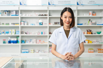 Beautiful asian woman pharmacist checks inventory of medicine in pharmacy drugstore. Professional Female Pharmacist wearing uniform standing near drugs shelves counter