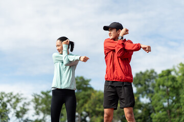 Couple asian jogging and running outdoors at sport stadium warming up stretching before workout. Happy healthy Man woman wearing sportswear jogging. Workout exercise Healthy and lifestyle.