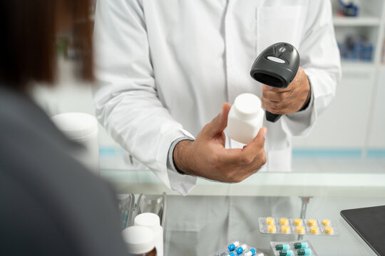 Payment with Barcode scanning to sell medicines. Pharmacist recommends medicines to customers. Professional Asian male pharmacist selling medications to female patient at drugstore shelves.