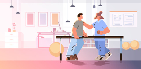 doctor helps patient after injury or medical operation during physio therapy man having physical rehabilitation in modern fitness studio