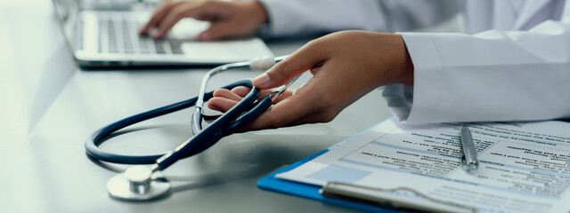 Doctor with stethoscope carefully review detailed medical report with laptop and diagnosing illness...
