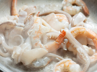 Grill prepared raw shrimp and squid on an iron plate.