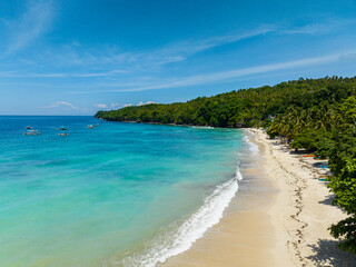 White sandy beach with turquoise sea water and waves. Samal Island. Davao, Philippines.