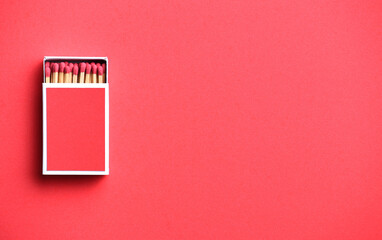 red matchstick in red matchbox on red paper background with copy space