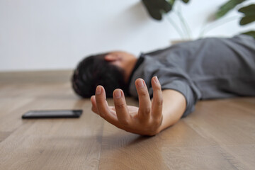 Unconscious young man lying on floor with epileptic seizures at home, male injure at home.