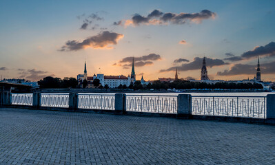 Fototapeta na wymiar Stone pier over the river with a colorful morning view on historical district of old Riga - the capital of Latvia