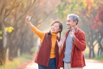 Foto op Plexiglas portrait young adult daughter and senior father smiling and taking a selfie together in autumn day outdoor,a family happy moment with love © Verin