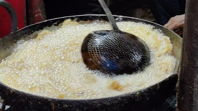 Footage of a person making samosa in hot oil in frying utensil. Delicious Indian fried patties
