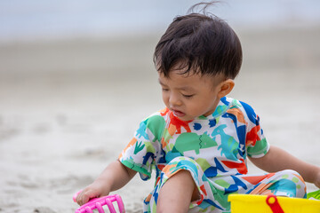 Happy 1-2 years old child enjoying playing on beach with splashing warm sea water