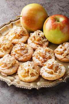 Sweet apple streusel shortbread cookies sprinkled with powdered sugar close-up in a plate on the table. Vertical