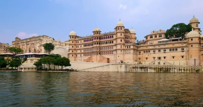 Udaipur City Palace view from moving boat on lake Pichola. Luxury white palace is Rajput architecture of Mewar dynasty rulers of Rajasthan and famous tourist Indian landmark. Incredible India heritage