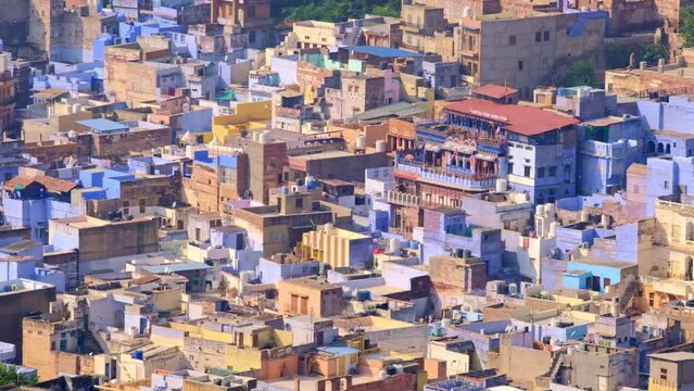 Jodhpur the Blue City aerial view. Blue painted houses and birds flying in the morning above brahmin houses, view from Mehrangarh Fort, Rajasthan, India. Camera zoom out