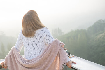 asian woman stands with her back to camera and enjoys the view of forest. and looking mountain view in morning sunrise with copy space. trip and relaxing. Travel vacations and lifestyle concept.