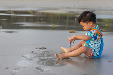 Happy Asian Chinese child playing in the beach. Kid having fun outdoors. Summer vacation and healthy lifestyle concept