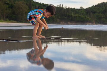 Happy Asian Chinese child playing in the beach. Kid having fun outdoors. Summer vacation and...