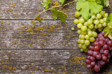 Grape with vine leaves on wooden table