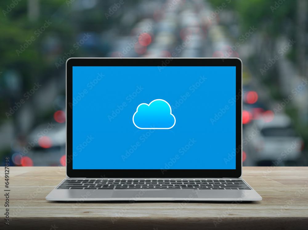 Poster cloud computing icon on modern laptop computer monitor screen on wooden table over blur of rush hour