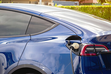 Charging electric vehicle with cable EV plugging in cable while charging electric car. EV charging...
