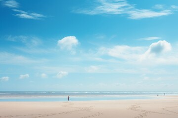 Obraz premium Silhouettes of people on the ocean coast under a blue sky with clouds, capturing a sunny, minimalist panorama