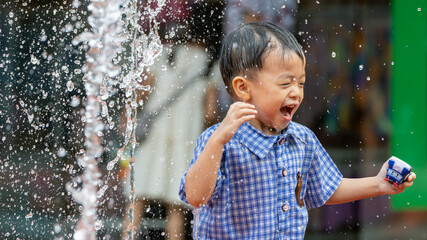 A carefree child reveling in the simple pleasures of summer, as they dance amidst the playful spray of a water fountain - obrazy, fototapety, plakaty