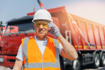 Fototapeta Man driver use phone for communication on background industry mining truck lorry. Concept professional industrial worker of logistic obraz