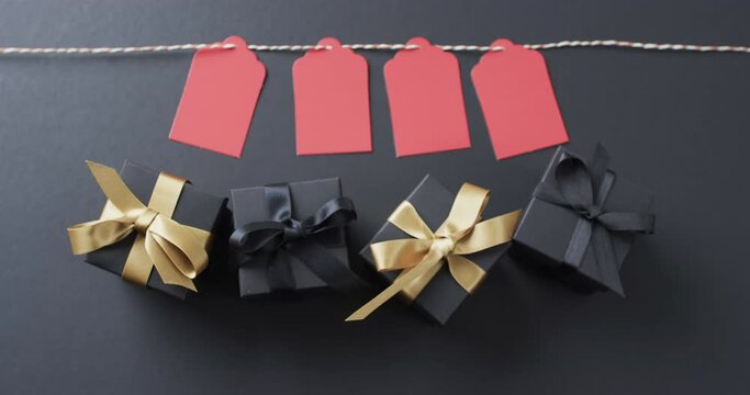 Video of gift tags on string, gift boxes with ribbons and copy space on black background