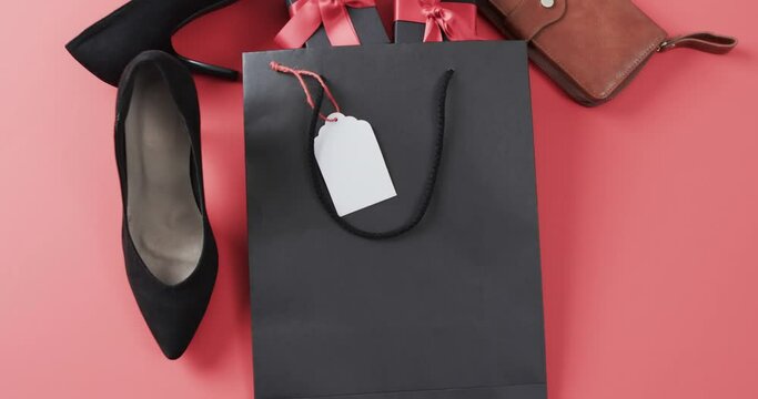 Video of gift bag, gift boxes with red ribbon, shoes, purse and copy space on red background