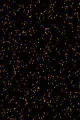 Golden sparkles and dashes on a black, vertically oriented background