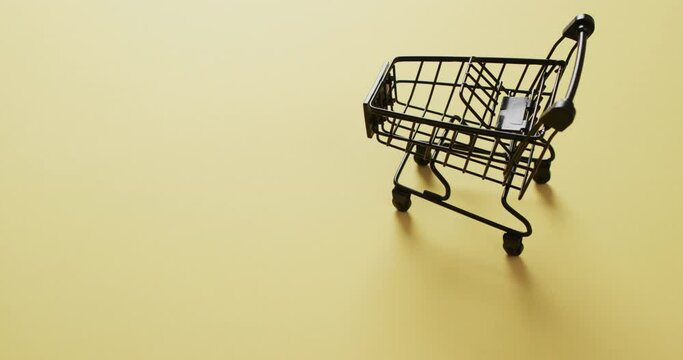 Video of empty shopping trolley with copy space on yellow background