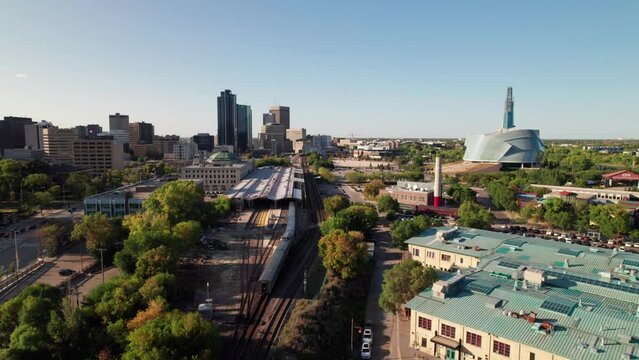 Aerial of Via Rail train entering Union Station in Winnipeg, MB. Human Rights Museum and Forks Market visible, 4K drone shot