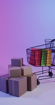 Vertical video of shopping trolley and shopping with copy space over pink neon background