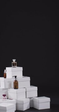 Vertical video of beauty products with white cardboard boxes with copy space over black background