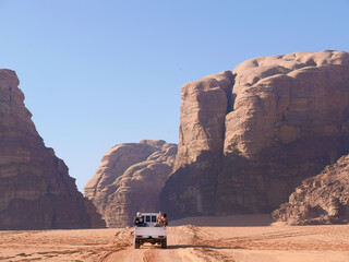 A pickup truck riding in Desert of Wadi Rum, red and orange sand dune landscape, UNESCO World Heritage site, Outdoor National Park, offroad adventure travel destination © Darr.di