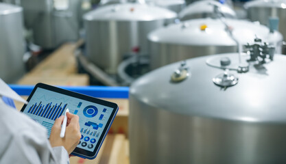 液体タンクをタブレットを持って点検するエンジニア