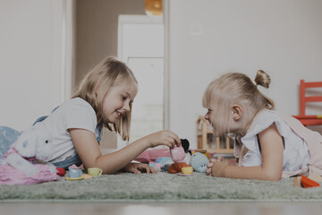Children playing with toy play tea set on the floor at home or kindergarten