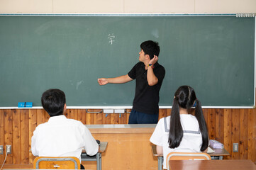学校の教室の教壇に立つ男性教師