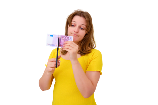 A woman cuts a bill of 500 euros with scissors, isolated on a white background. Wasted money spent on apartment renovation