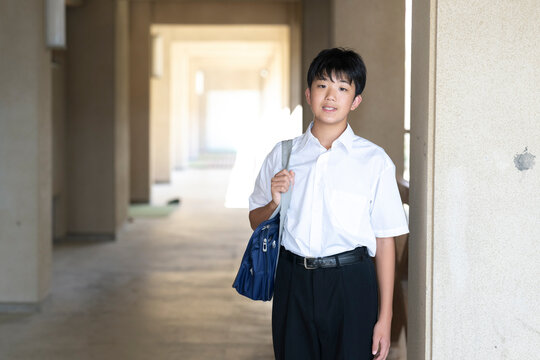 学校の校舎と学生服を着た男子学生